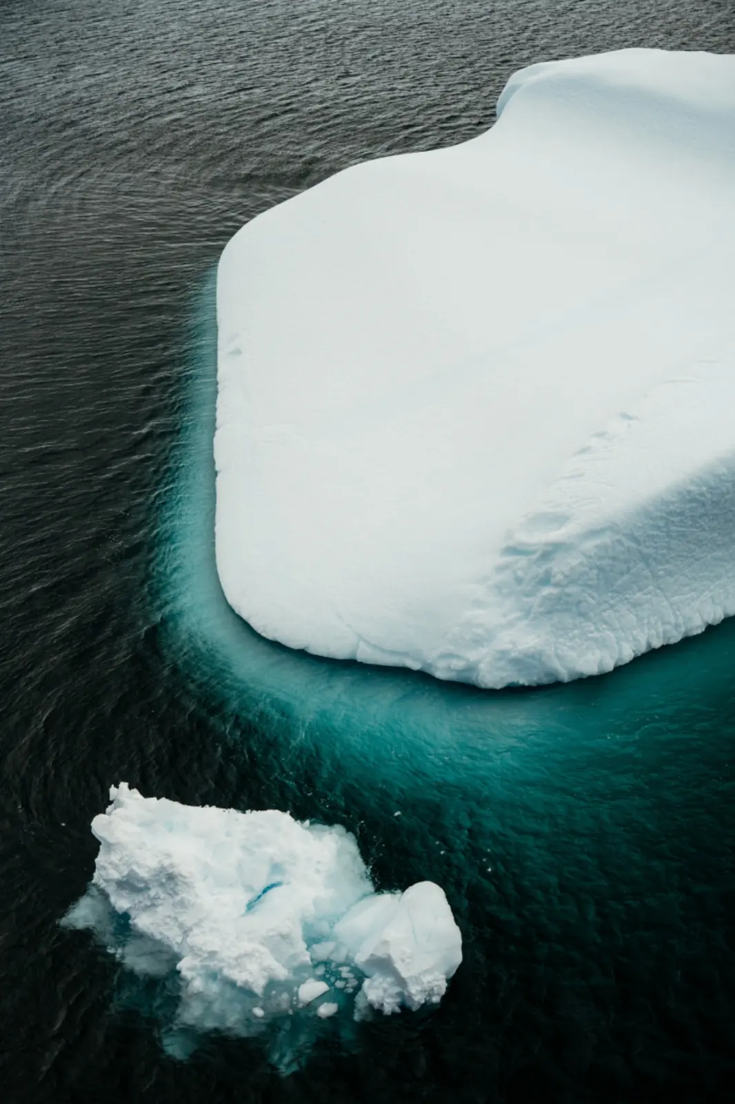 Abstract aerial view of snow-covered ice edged by turquoise water.