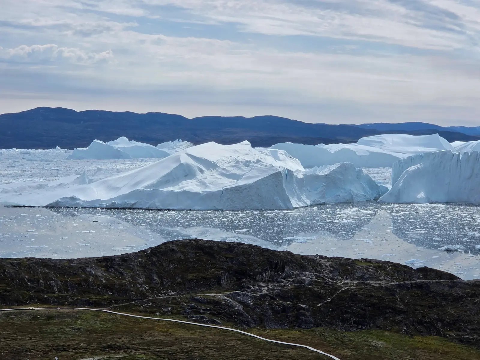 Wide field of monumental icebergs along a polar coast.