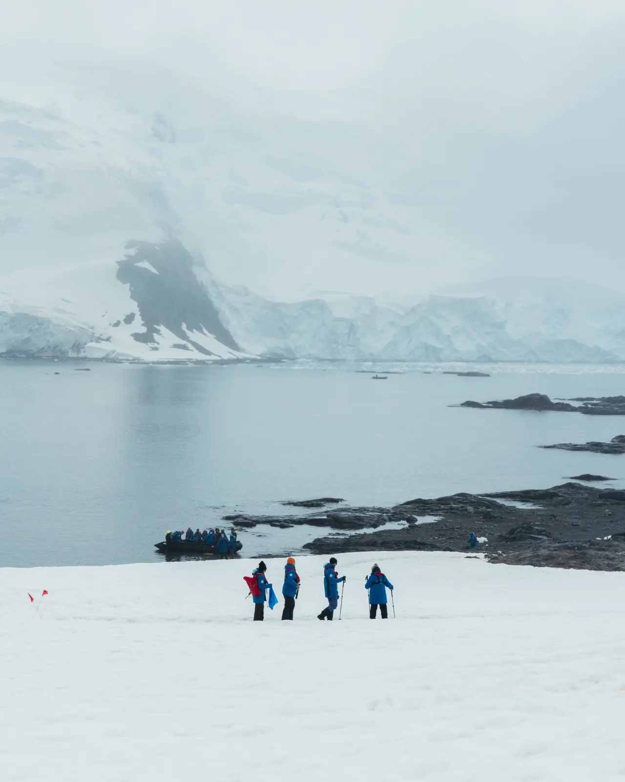 Polar expedition guests walking toward a quiet icy bay.