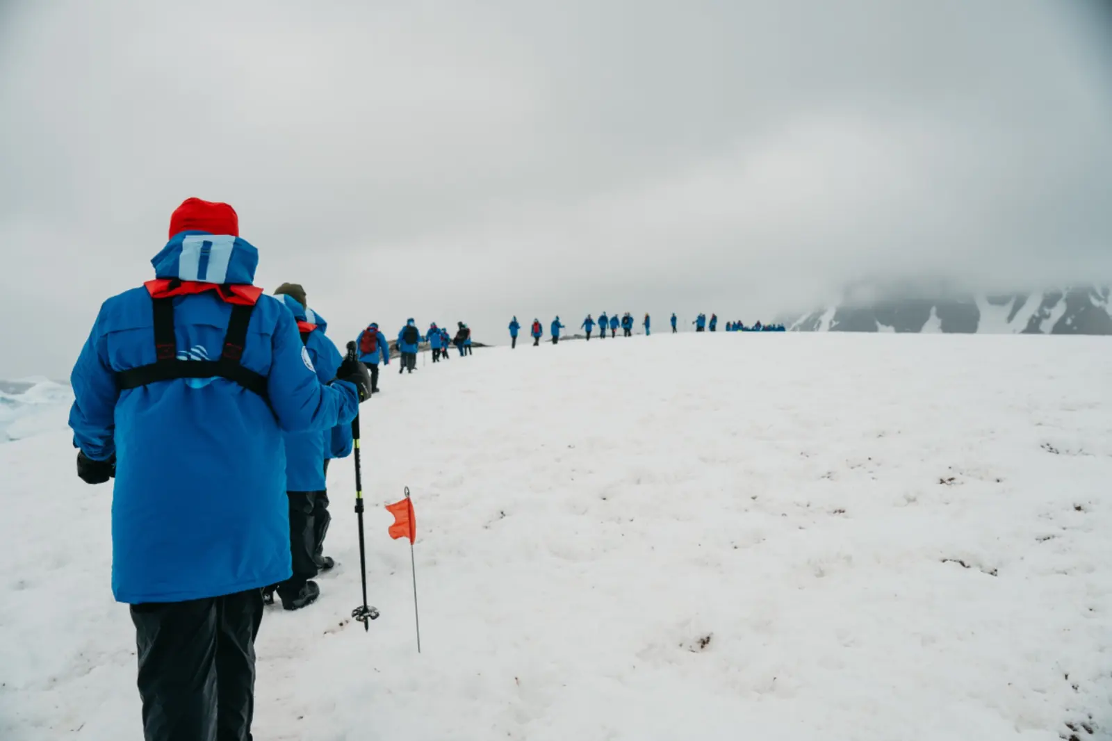 Expedition travellers hiking across a wide snowfield.