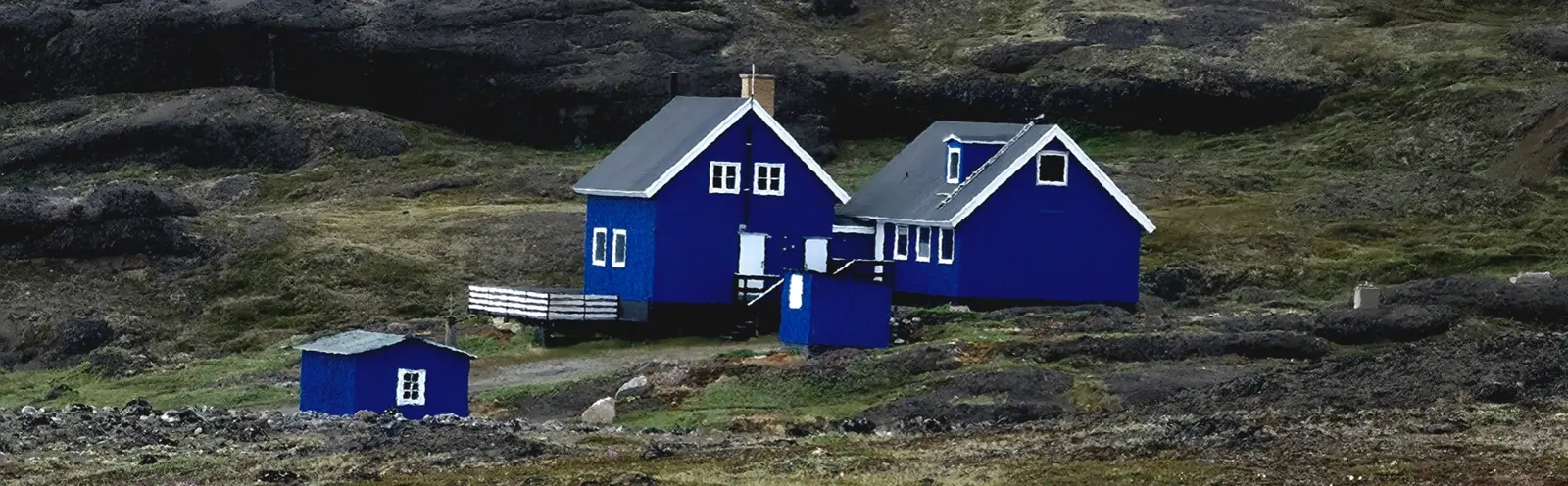 Blue houses set against a rugged Arctic hillside.